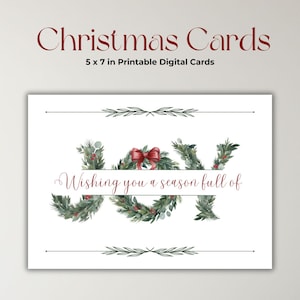 Può includere: Un biglietto di Natale bianco con le parole "Christmas Cards" in corsivo bordeaux. Il biglietto misura 12,7 x 17,8 cm e presenta la parola "JOY" decorata con verde e un fiocco rosso. È incluso anche il testo "Wishing you a season full of".