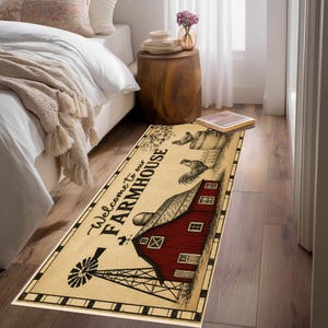 May include: A rectangular area rug featuring a cream-colored background with a black border. The design includes a red barn, a black windmill, a rooster, and the text Welcome to our FARMHOUSE in black script and block lettering.
