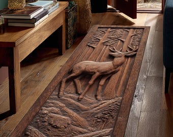 May include: A rectangular, brown wooden rug with a carved relief of a deer in a forest scene. The deer is in the center, surrounded by trees and a mountainous landscape. The rug is placed on a wooden floor.