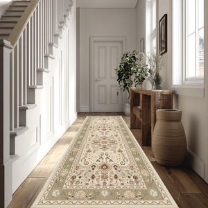 May include: A hallway runner rug with an ornate floral pattern in cream, beige, and muted green tones. The rug features a detailed border and is placed on a wooden floor, enhancing the entryway's aesthetic.