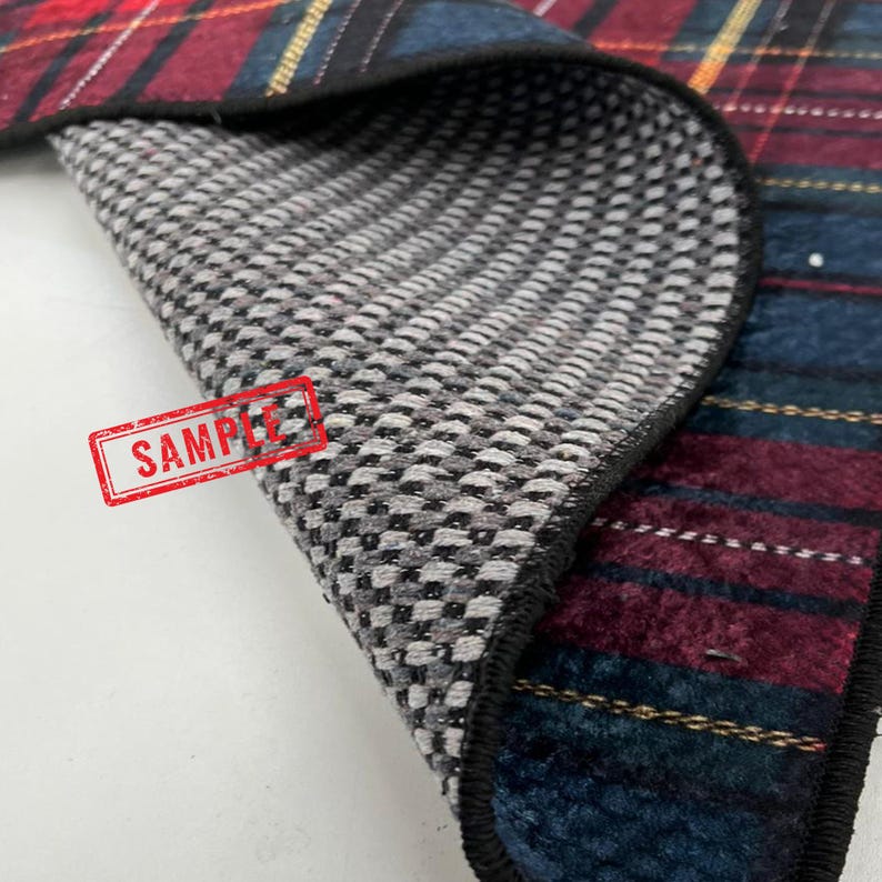 May include: Close-up of a plaid fabric with a gray and white patterned underside. The plaid features red, blue, and yellow stripes. The word "SAMPLE" is stamped in red on the gray side.