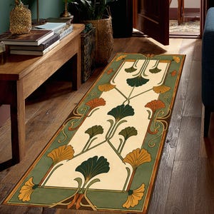 May include: A rectangular runner rug featuring a cream-colored center panel decorated with symmetrical, stylized ginkgo leaf motifs in shades of dark green, orange, and yellow, framed by a wide, muted green border with matching leaf patterns.