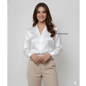 May include: A white satin shirt with a V-neck and long sleeves. The shirt has a glossy finish and is buttoned up. The model is wearing beige trousers. The text "PremiumVastr" is visible on the right side of the image.