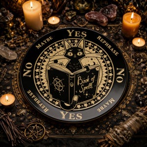 Puede incluir: Una planchette negra y dorada con un gato leyendo un libro titulado "Book of Spells". La planchette tiene las palabras "Yes", "No", "Maybe" y "Rephrase" alrededor del borde. La imagen está rodeada de velas y otros objetos místicos.