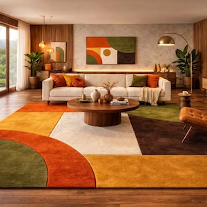 Op de afbeelding: Een moderne woonkamer met een groot, kleurrijk tapijt in tinten oranje, geel, groen en bruin. De kamer heeft een witte bank, een houten salontafel en een leren fauteuil. Grote ramen bieden uitzicht op een weelderig groen landschap.