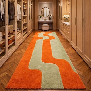 Könnte beinhalten: Ein langer, rechteckiger Teppich mit einem abstrakten Design in einem begehbaren Kleiderschrank. Der Teppich hat ein wellenförmiges Muster in Orange und Hellgrün. Der Schrank hat Holzschränke und einen Fischgrät-Holzboden.