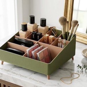 May include: An olive green, ribbed makeup organiser with multiple compartments containing various cosmetics, including foundation bottles, lipsticks, and makeup brushes. The organiser features small, light-coloured wooden legs and is labelled Large Modern Makeup Organizer - 3D Printed Ribbed.