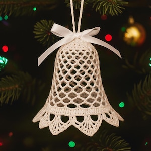 May include: A white, crocheted bell-shaped Christmas ornament with a delicate openwork design. The ornament is adorned with a white satin bow and a loop for hanging. It hangs from a green Christmas tree with colorful lights and other ornaments.