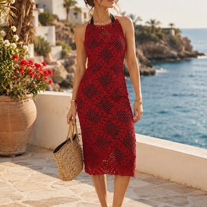 Puede incluir: Vestido halter rojo de ganchillo con un diseño floral. El vestido, a la altura de la rodilla, tiene un forro negro. Se lleva un bolso tote de paja y sandalias. El fondo muestra una escena costera con edificios y el mar.