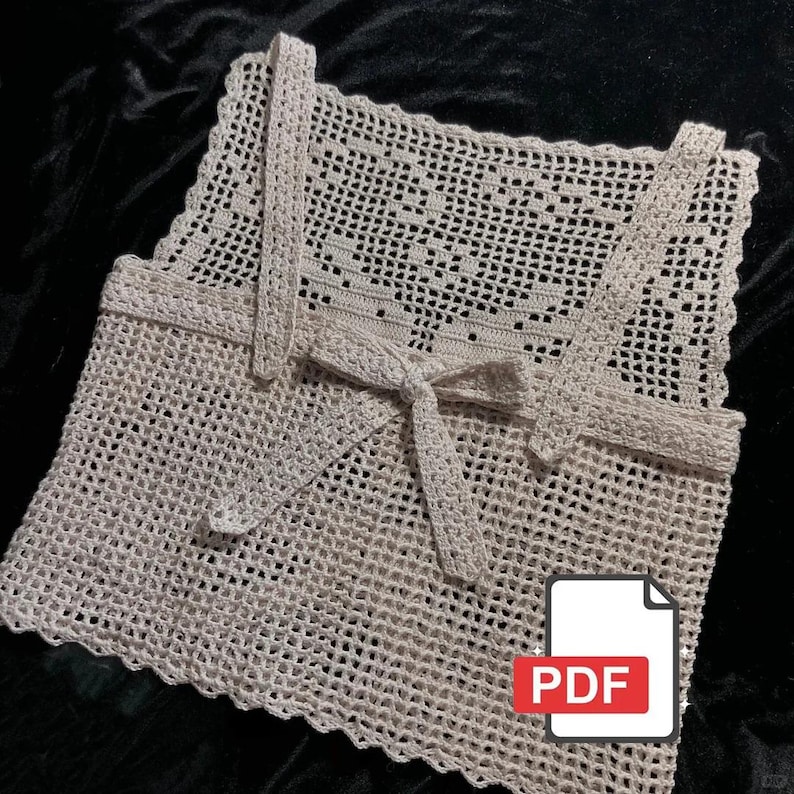Peut inclure: Un haut en crochet cr&egrave;me &agrave; tissage ouvert, avec des bretelles et une fermeture &agrave; nouer. Le haut pr&eacute;sente un motif d&eacute;licat et dentelle et un bord festonn&eacute;. Une ic&ocirc;ne PDF est visible dans le coin inf&eacute;rieur droit. V&ecirc;tement fait main.