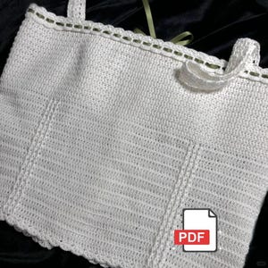 May include: A white, crocheted top with a scalloped edge and straps. The top has a textured pattern and is trimmed with a thin green thread. A PDF icon is in the lower right corner.
