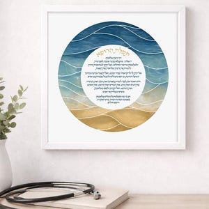 May include: A framed print featuring a circular design with a beach and ocean scene in shades of blue and gold. The print contains text in a foreign language. A stethoscope and a vase with greenery are in the foreground.