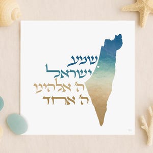 May include: A square white print featuring the shape of Israel in shades of blue and tan, with Hebrew text. The print is surrounded by seashells and a starfish on a beige background.