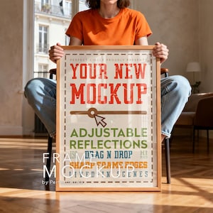 May include: A wooden framed mockup with the text "YOUR NEW MOCKUP" in red, and other text in green, orange, and blue. The mockup is held by a person wearing an orange shirt and blue jeans. The mockup is in a room with natural light.