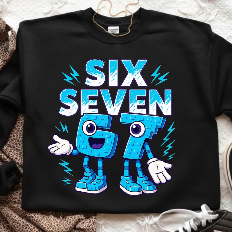 May include: Black sweatshirt with the words "SIX SEVEN" in large, light blue letters. Below the words are the numbers 6 and 7, designed as cartoon characters with arms, legs, and smiling faces. Lightning bolt graphics are on the sides.