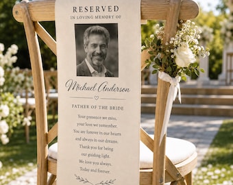 May include: A wooden cross-back chair featuring a hanging memorial sign with the text RESERVED IN LOVING MEMORY OF, a black and white portrait of Michael Anderson, the name Michael Anderson, and a poem, decorated with a white rose and baby's breath.