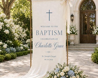 May include: A vertical cream-colored fabric banner suspended on a metal frame, featuring a blue cross and the text: Welcome to the Baptism Celebration of Charlotte Grace, St. Joseph Chapel, 06.14.2026. A large cream ribbon bow is tied at the top.