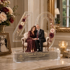 May include: A clear acrylic 40th anniversary display featuring a large number 40 with floral accents, a miniature sofa with a couple, and a base engraved with "David & Margaret Celebrating 40 Wonderful Years Wedding Day 1986 Ruby Anniversary 2026".