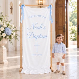 Puede incluir: Una pancarta de tela blanca suspendida de un marco de madera con cintas azul claro, con el texto "WELCOME TO Noah's Baptism" en letra azul claro, un icono de cruz azul claro y la fecha "18.10.2026" impresa en azul claro.