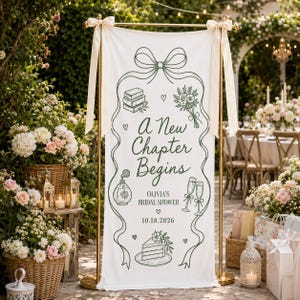 Puede incluir: Una pancarta vertical de tela blanca suspendida en un soporte de metal dorado con cintas color crema. La pancarta presenta dibujos lineales verdes de libros, flores, frasco de perfume, copas de champán y pastel, con el texto A New Chapter Begins, OLIVIA'S BRIDAL SHOWER y 18.10.2026.