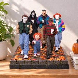 May include: A collection of six horror movie character action figures standing on a stone-textured base covered in orange and red autumn leaves. Each figure wears casual clothing and holds a white disposable cup with a red straw in their hand.