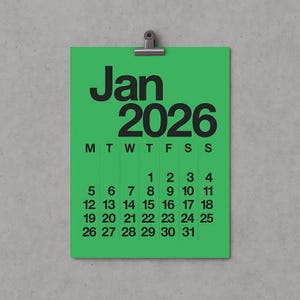 Op de afbeelding: Een groene januari 2026 kalenderpagina, vastgehouden door een zilveren clip. De kalender toont de dagen van de week en de data van 1 tot en met 31. De maand en het jaar zijn in vette zwarte letters.