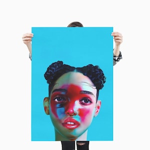 Op de afbeelding: Een portretposter met een persoon met donker haar gestyled in twee knotjes. Het gezicht is beschilderd met levendige rode, blauwe en roze tinten tegen een helderblauwe achtergrond. De ogen van de persoon zijn donker en expressief.