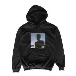 May include: Black hooded sweatshirt with a front pocket and a drawstring hood. The sweatshirt features a rectangular graphic on the chest with a blurred silhouette of a person against a blue and white background. The graphic includes a parental advisory label.