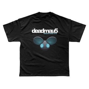 Peut inclure: T-shirt noir avec le logo Deadmau5 en blanc et le texte "for lack of a better name" en dessous. Le design comprend une tête de souris stylisée avec des oreilles bleues et des yeux bleus brillants. Un t-shirt à col rond classique.