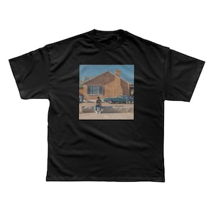 May include: Black t-shirt featuring a printed image of a person sitting in front of a brick house and a teal car. The image has a vintage aesthetic. The t-shirt is made of a soft, comfortable material.