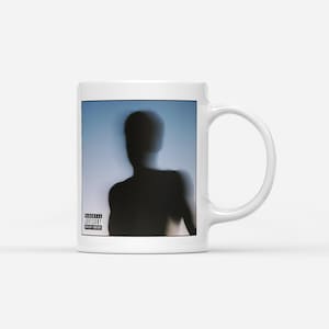 May include: White ceramic mug featuring a blurred silhouette of a person against a blue background. The mug has a Parental Advisory Explicit Content label. The mug has a curved handle.