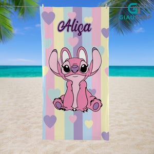 A colorful towel featuring a cartoon character, likely Stitch from the movie Lilo & Stitch, with the name "Aliza" printed on it. The towel is hanging on a line against a backdrop of palm trees and a beach.