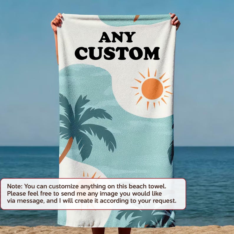 A person is holding a beach towel with a tropical design, including palm trees and a sun, against a backdrop of the ocean.