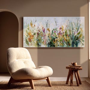 Pu&ograve; includere: Un dipinto floreale astratto su tela, con una vibrante gamma di colori. L'opera d'arte presenta un campo di fiori nelle tonalit&agrave; del giallo, del viola e del verde, con uno sfondo azzurro. Il dipinto &egrave; esposto sopra una sedia color crema.