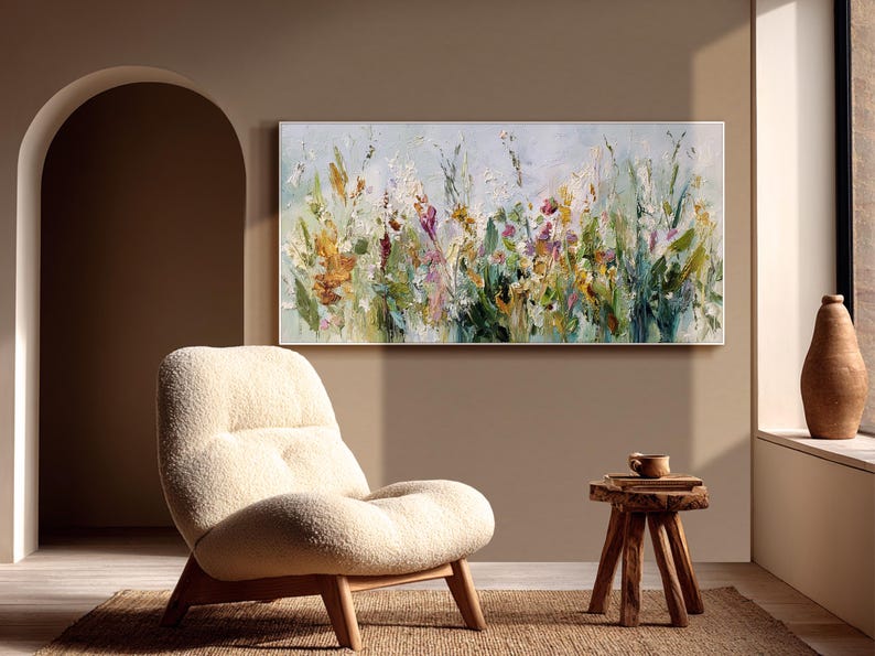Pu&ograve; includere: Un dipinto floreale astratto su tela, con una vibrante gamma di colori. L'opera d'arte presenta un campo di fiori nelle tonalit&agrave; del giallo, del viola e del verde, con uno sfondo azzurro. Il dipinto &egrave; esposto sopra una sedia color crema.