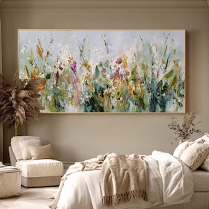 Pu&ograve; includere: Un dipinto astratto di un campo di fiori selvatici nei toni del verde, bianco, giallo e viola. L'opera d'arte &egrave; incorniciata in oro e appesa sopra un letto in una camera da letto.