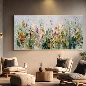 Pu&ograve; includere: Grande dipinto floreale astratto con cornice bianca. L'opera presenta uno stile impasto strutturato con una tavolozza di verdi, gialli, arancioni e viola. Il dipinto &egrave; esposto sopra un'area salotto con mobili dai toni neutri.