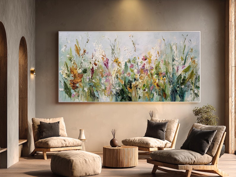 Pu&ograve; includere: Grande dipinto floreale astratto con cornice bianca. L'opera presenta uno stile impasto strutturato con una tavolozza di verdi, gialli, arancioni e viola. Il dipinto &egrave; esposto sopra un'area salotto con mobili dai toni neutri.