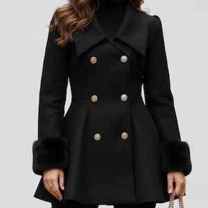 May include: Black double-breasted coat with gold buttons and faux fur cuffs. The coat has a flared skirt and a wide collar. A black handbag with a gold chain strap is held in the hand.