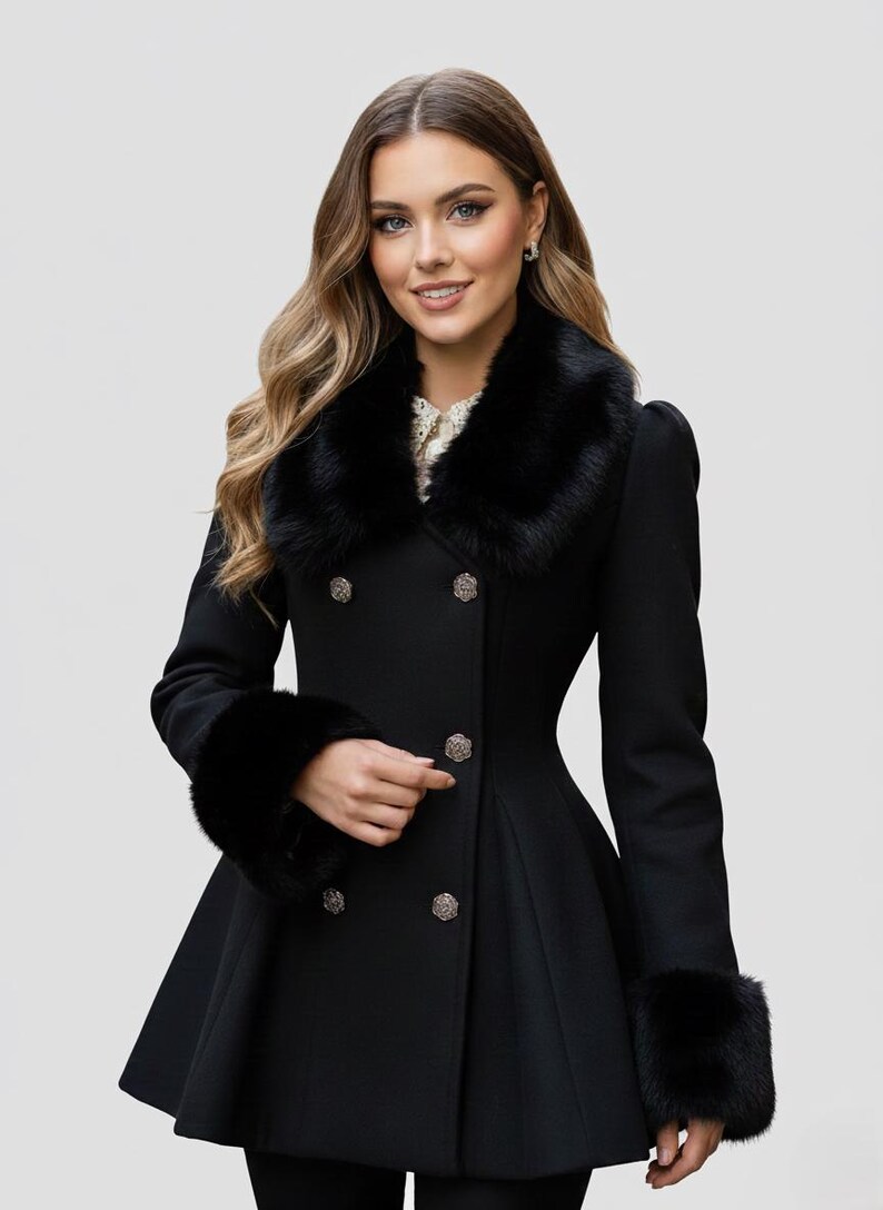 May include: A black double-breasted coat with a faux fur collar and cuffs. The coat features decorative silver buttons and a flared skirt. The model is wearing the coat. The coat is a classic style.