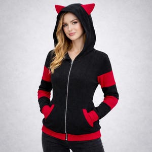 May include: Black zip-up hoodie with red accents and cat ears on the hood. The hoodie has red stripes on the sleeves and red pockets. The zipper is silver.