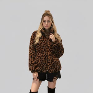 Puede incluir: Chaqueta con estampado de leopardo marr&oacute;n y negro, con cierre de cremallera. La chaqueta tiene cuello alto y mangas largas. La modelo lleva shorts negros y botas negras.