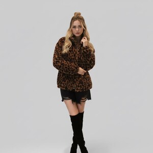 Puede incluir: Chaqueta de piel sint&eacute;tica con estampado de leopardo marr&oacute;n y negro con cuello alto. La chaqueta est&aacute; abotonada y se usa con pantalones cortos negros y botas negras hasta la rodilla. La modelo tiene el pelo rubio.