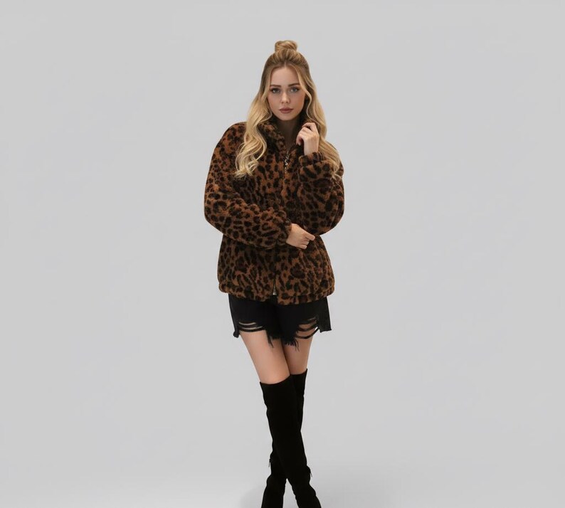 Puede incluir: Chaqueta de piel sint&eacute;tica con estampado de leopardo marr&oacute;n y negro con cuello alto. La chaqueta est&aacute; abotonada y se usa con pantalones cortos negros y botas negras hasta la rodilla. La modelo tiene el pelo rubio.