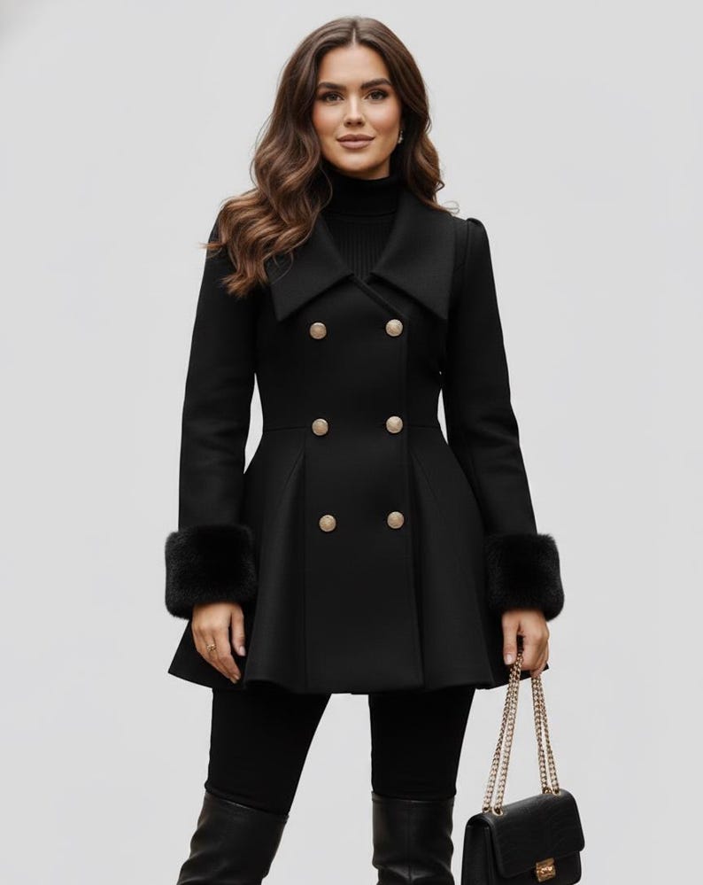 May include: Black double-breasted coat with gold buttons and faux fur cuffs. The coat has a flared skirt and a wide collar. A black handbag with a gold chain strap is held in the hand.