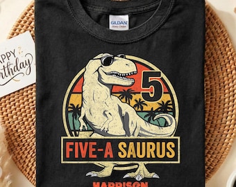 Può includere: Maglietta Gildan nera con grafica di dinosauro con occhiali da sole, il numero 5 e la scritta "FIVE-A SAURUS" e "HARRISON". Il design è ambientato su uno sfondo di tramonto. Tema compleanno.