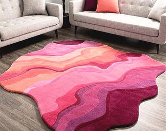 May include: A large, irregularly shaped rug with a layered design in shades of pink, red, and orange. The rug's pattern resembles flowing waves or abstract shapes, adding a modern touch to the room's decor.