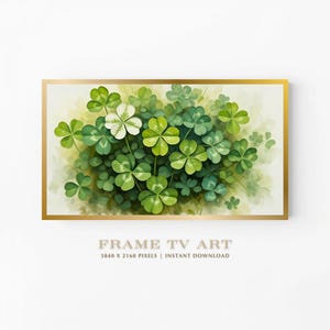 May include: A framed artwork featuring a cluster of green and white four-leaf clovers. The clovers are set against a soft, light green and yellow background. The frame is gold, and the text "FRAME TV ART" is visible at the bottom.