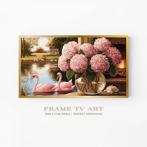May include: Digital art print in a gold frame. The image shows a lake scene with two pink swans and a vase of pink hydrangeas. The background includes a fireplace. The artwork is 97.5 cm x 54.8 cm.