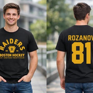 May include: Black t-shirt with gold lettering and a hockey design. The front reads "RAIDERS" above "BOSTON HOCKEY" and "EST. NINETEEN TWENTY-FOUR." The back shows "ROZANOV" and the number "81."